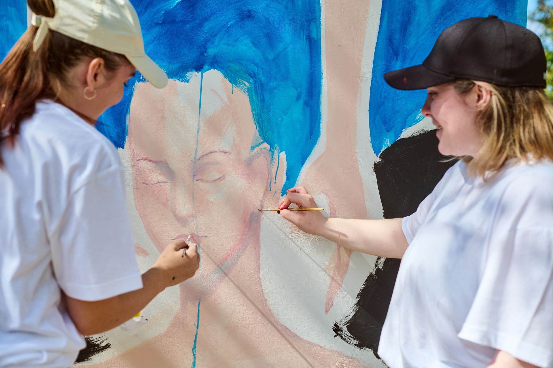 Two young women collaborating on large wall art
